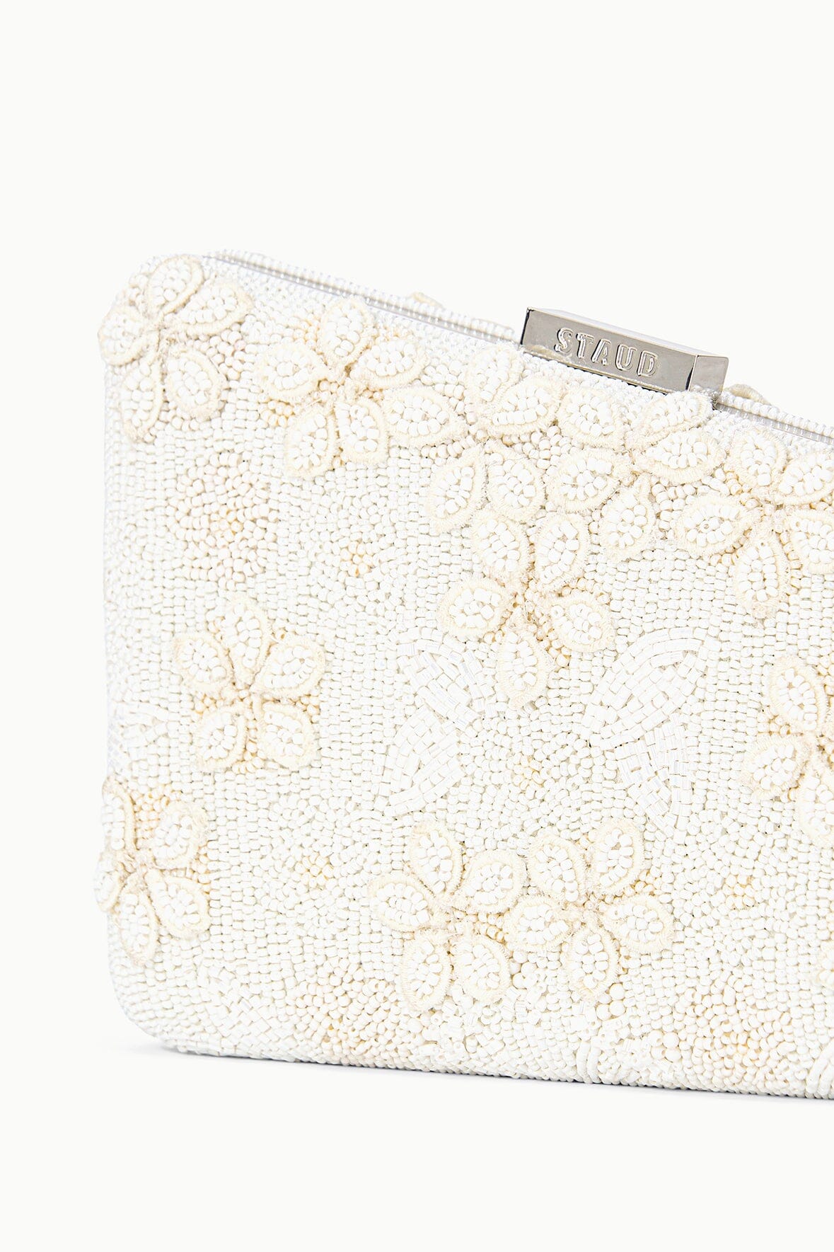 Close-up off-white beaded clutch, floral pattern, metal logo clasp