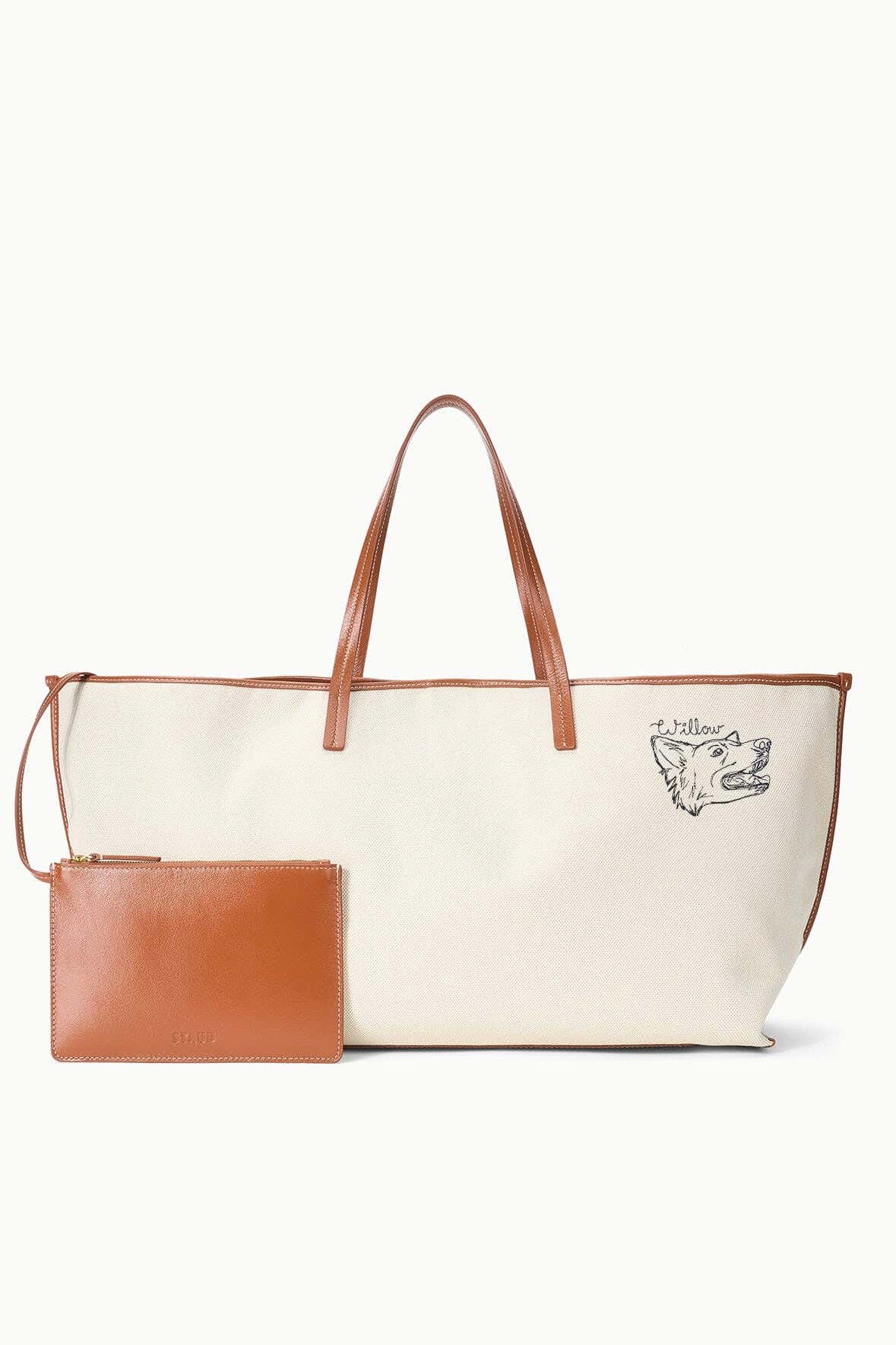 Cream canvas tote bag with tan handles, dog logo, and matching leather pouch