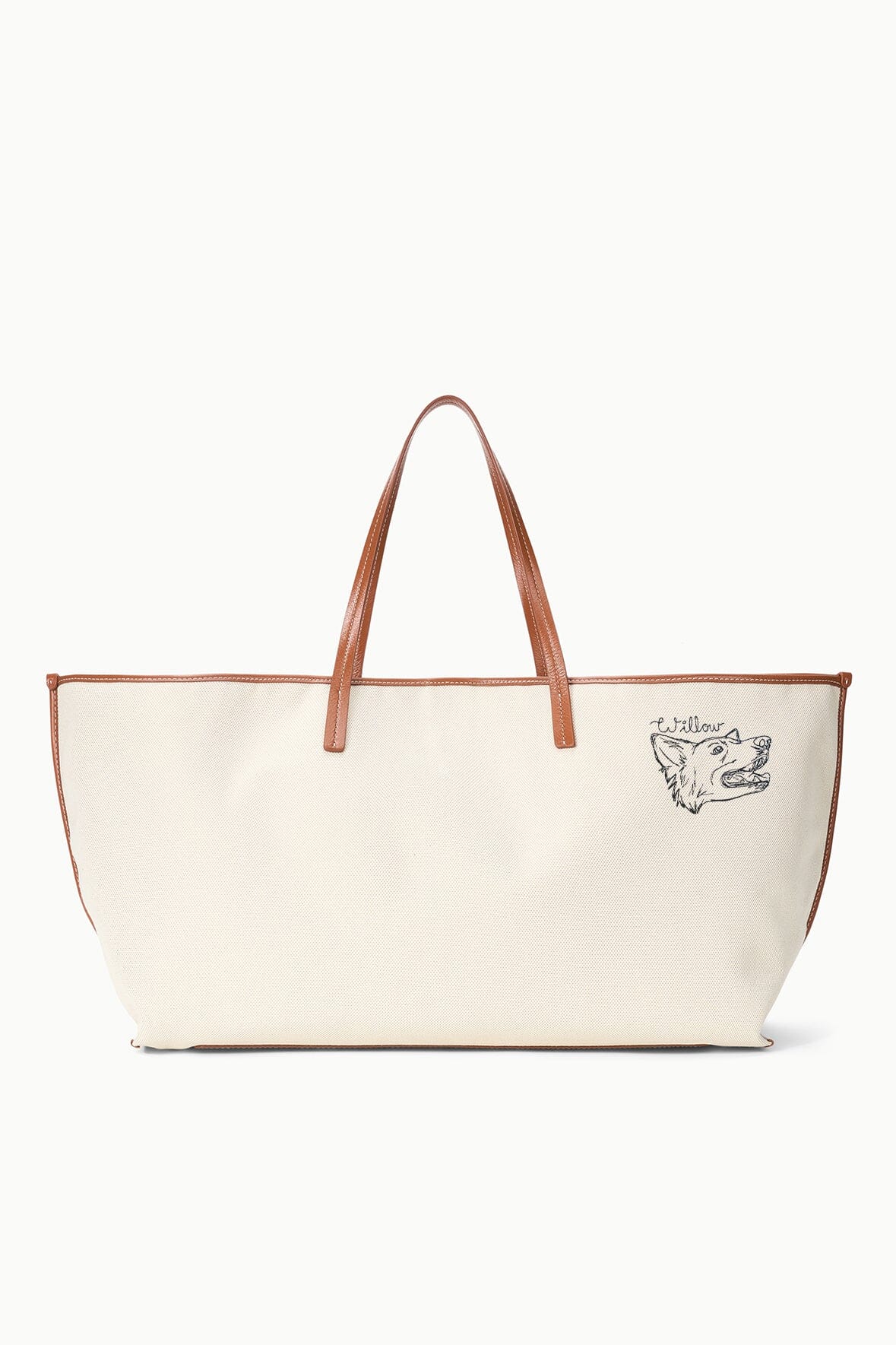 Cream canvas tote bag with tan leather handles and dog-face logo patch