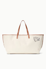 Cream canvas tote bag with tan leather handles and dog-face logo patch