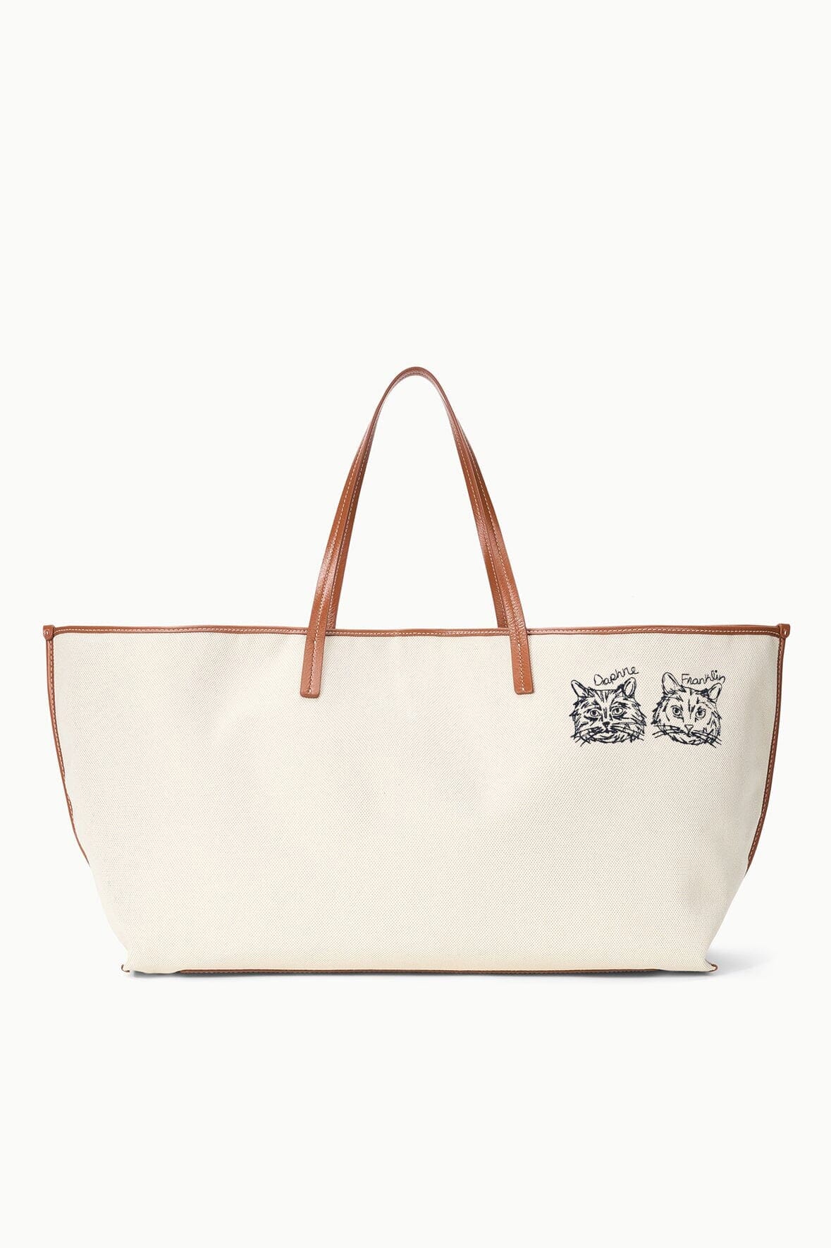 Cream canvas tote bag with tan leather handles and two dog-face illustrations