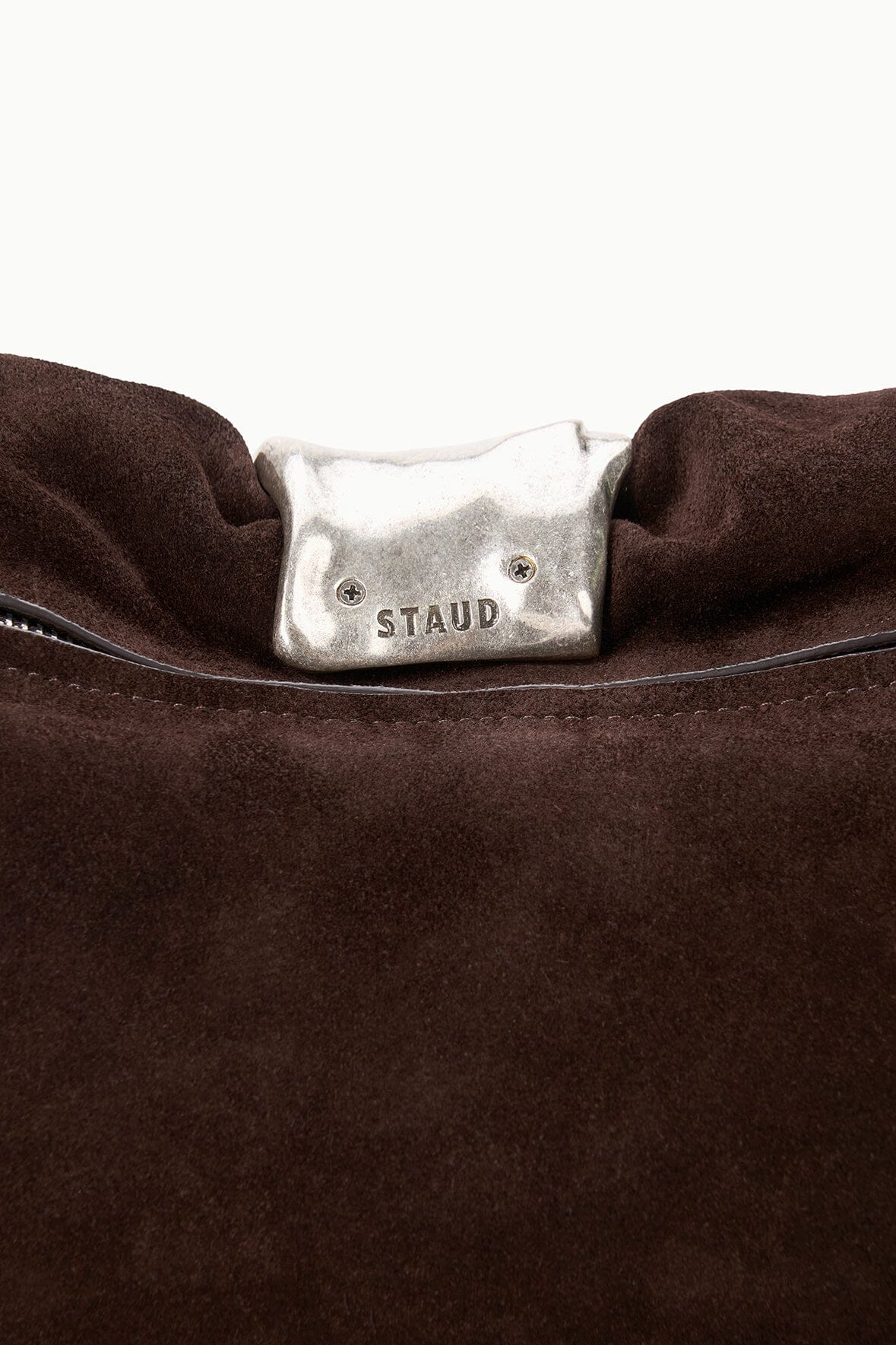 Espresso suede cuff clutch close-up with silver snap bar and STAUD logo