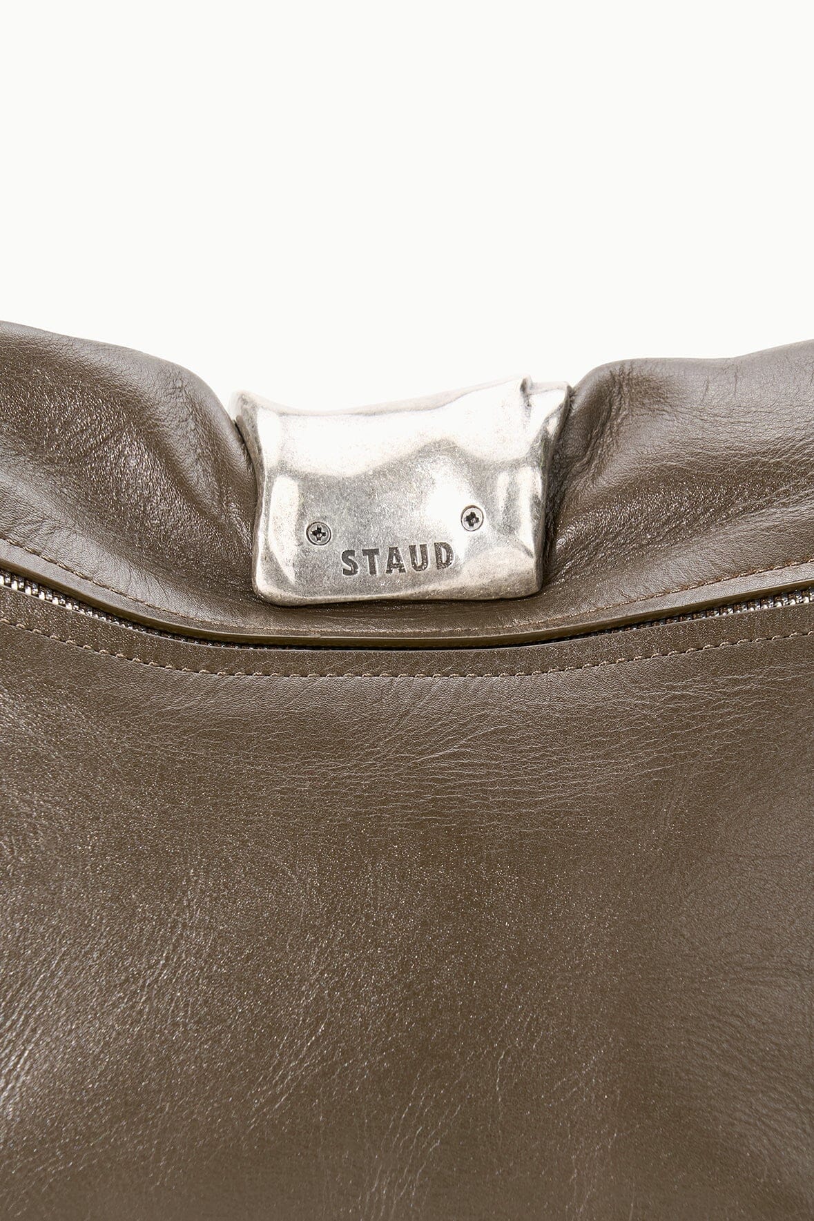 Dark taupe leather cuff clutch top with STAUD logo plate and zipper detail