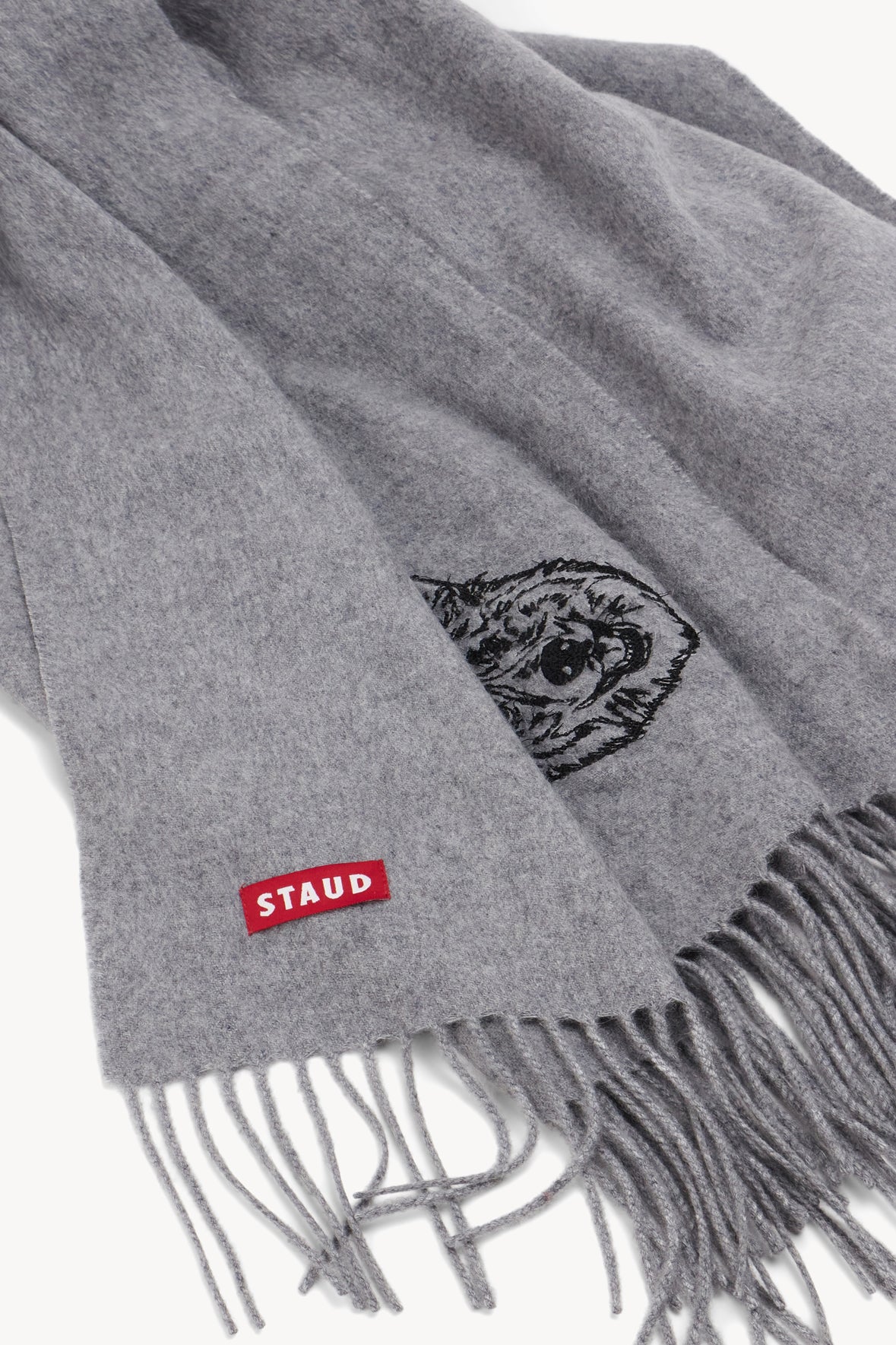 Grey cashmere blanket detail with embroidered crest and fringe edge