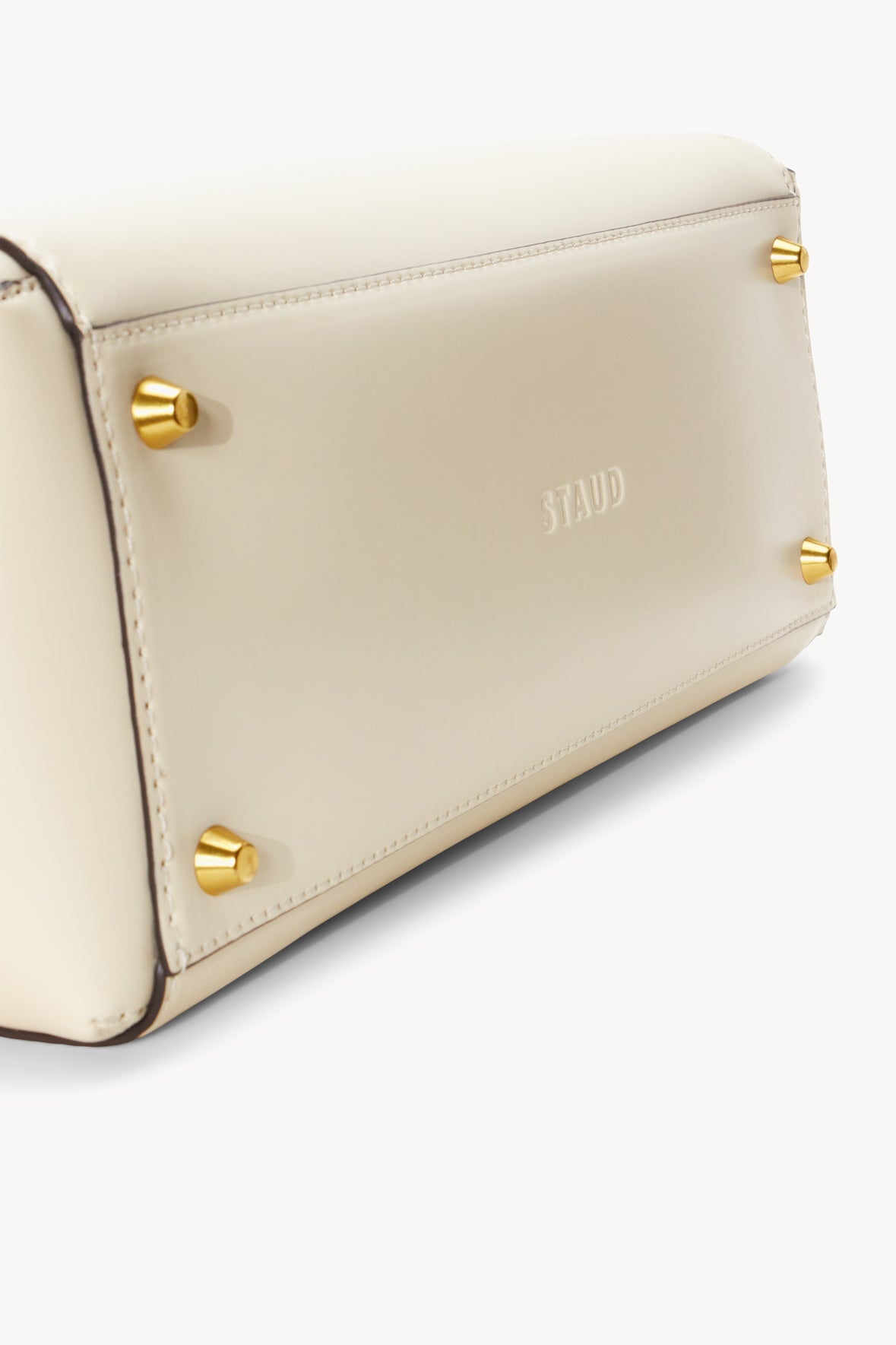 Cream leather tote side with gold-tone snap buttons and contrast stitching.