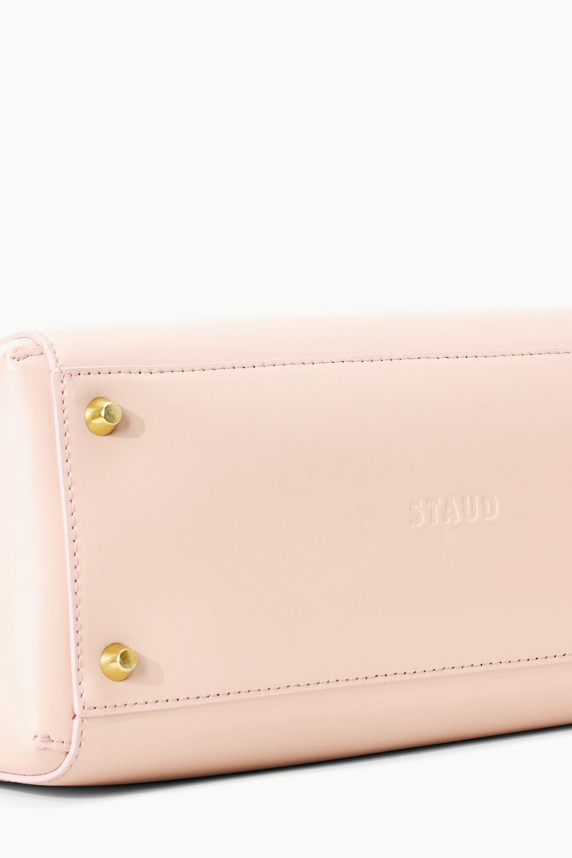 Blush leather bag front panel with embossed logo and gold snap details