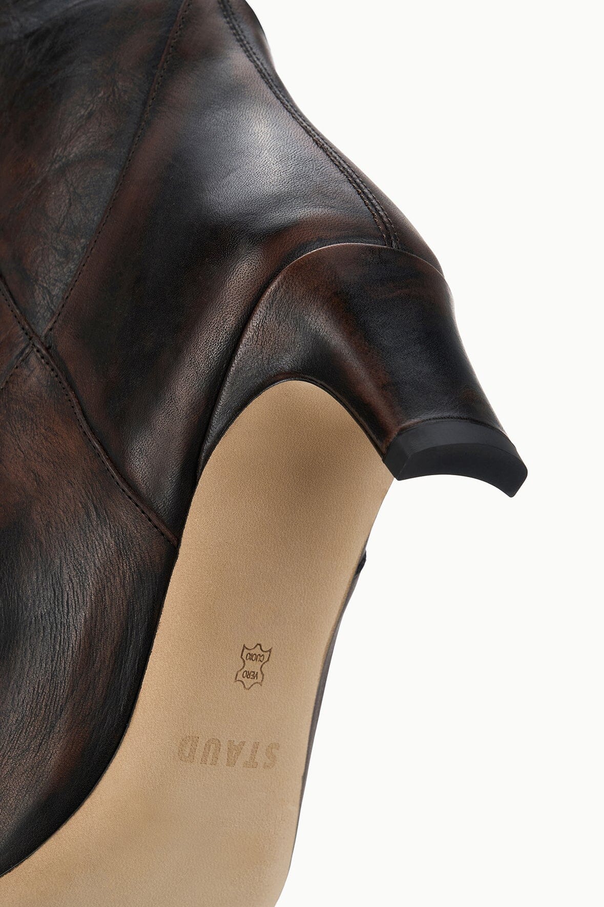 Inside cuff of dark brown western boot with beige lining and small brand mark