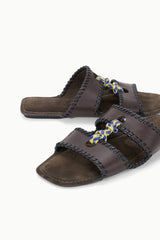 Espresso-brown slide sandals with braided straps and blue-yellow bow accents