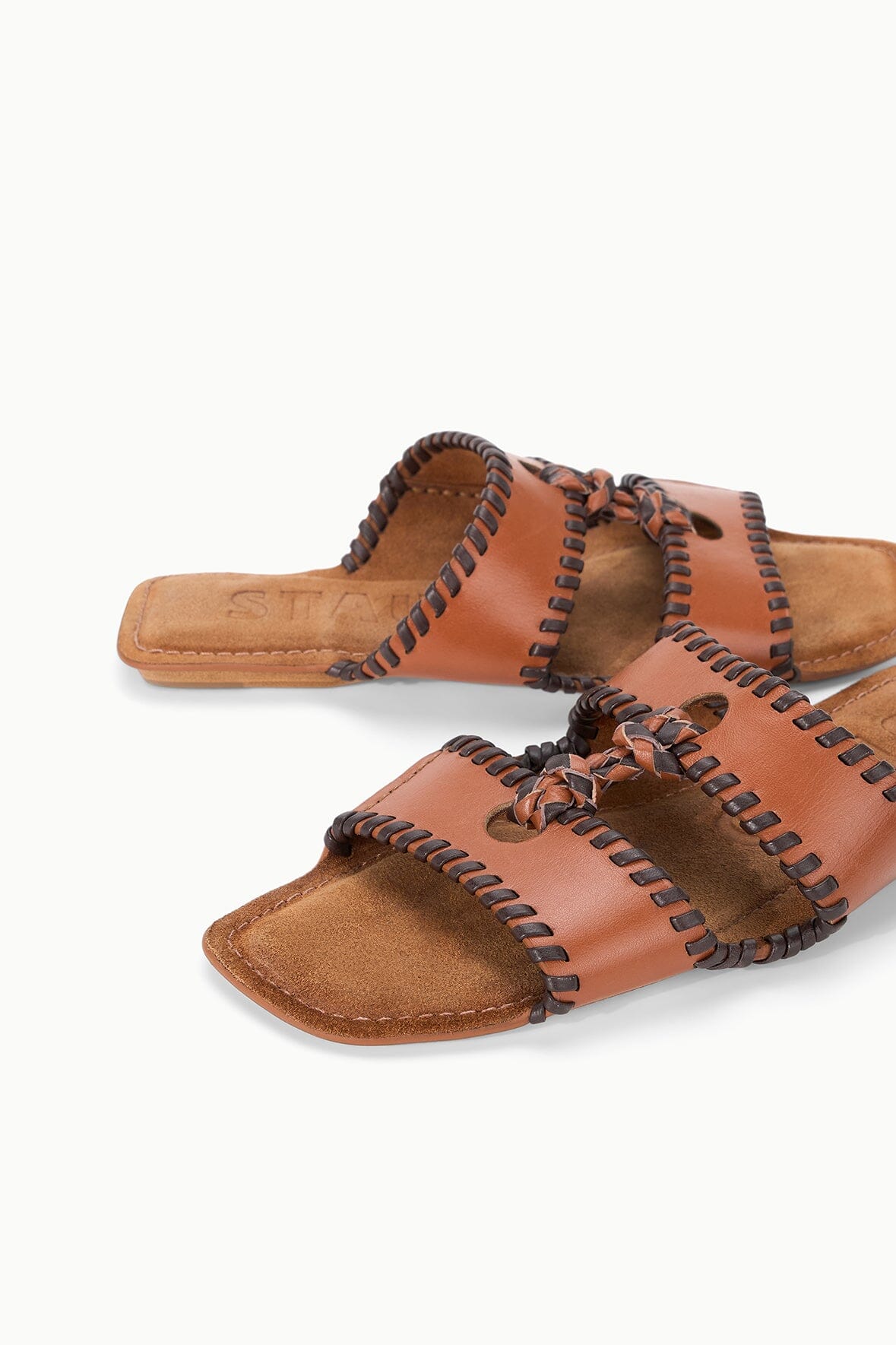 Tan slide sandals with braided strap knots and textured stitched trim