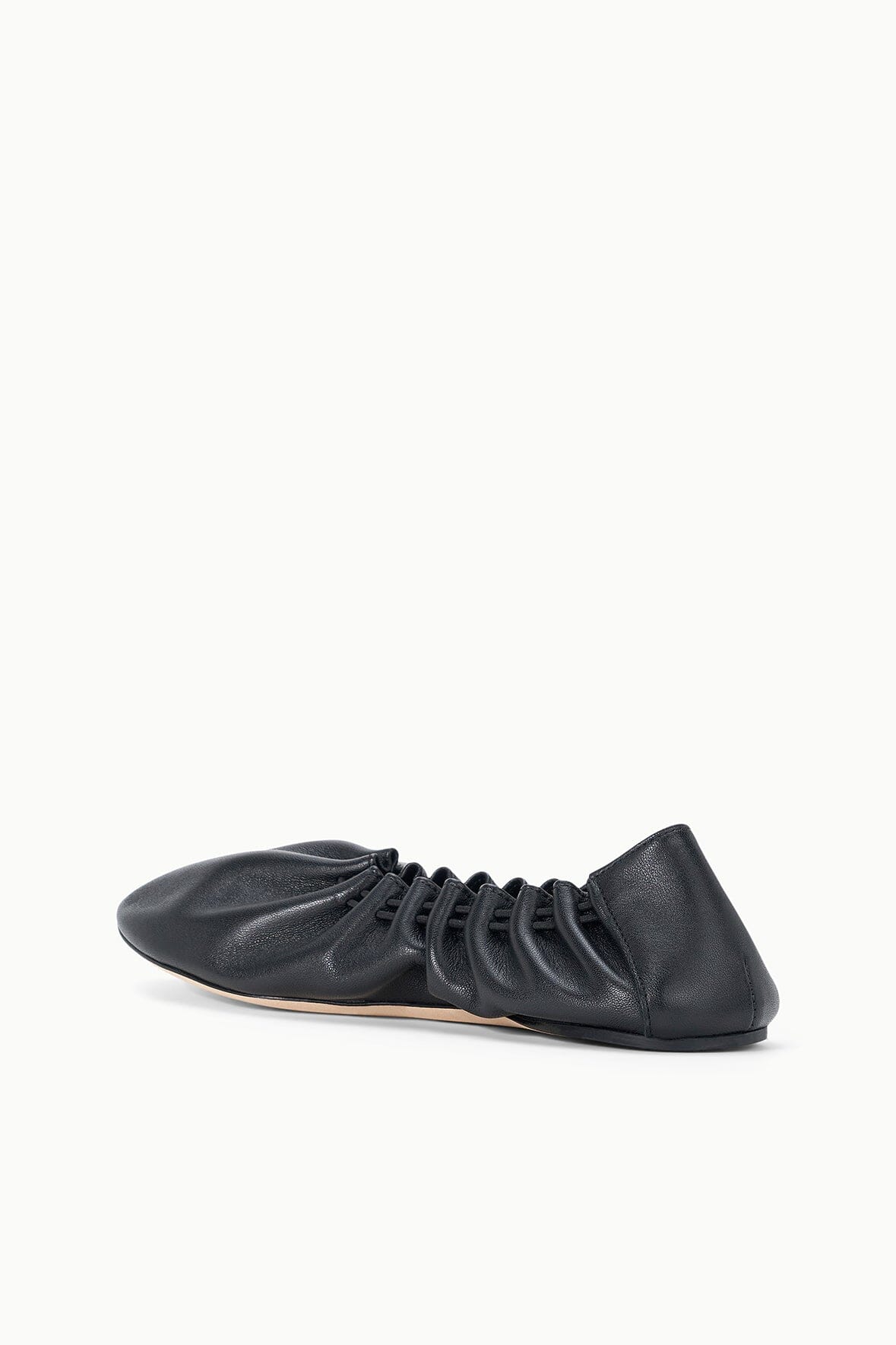 Black flat sneaker shoe angled view, ruched upper and lace-up detailing