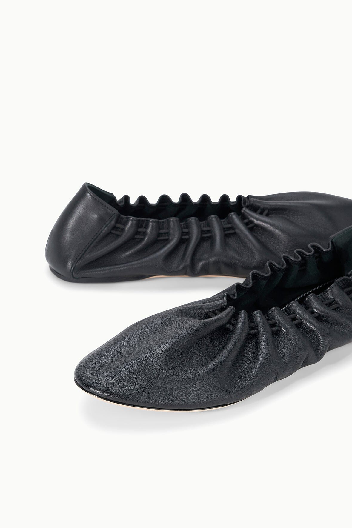 Pair of black flat sneakers with ruched uppers and lace-up eyelets