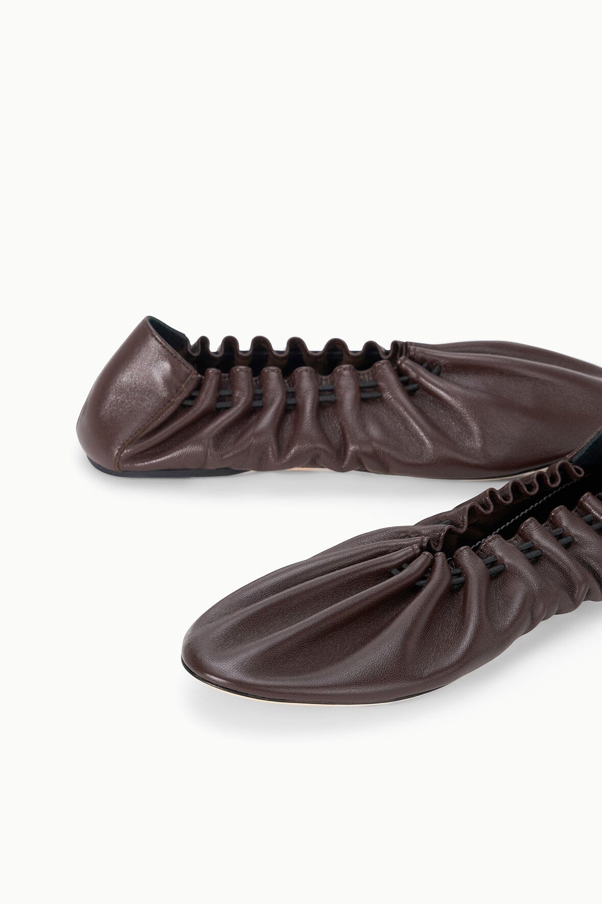 Pair of espresso-brown flat shoes, close side view of gathered uppers