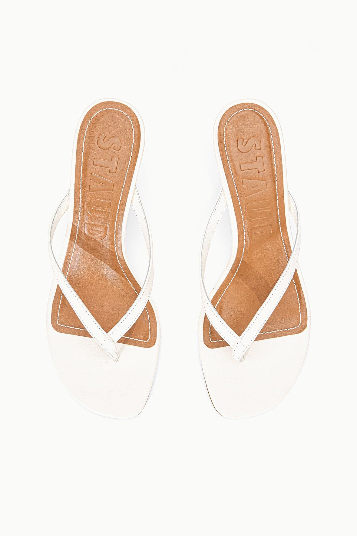 White kitten-heel sandals with crisscross straps, open toe, and tan insole