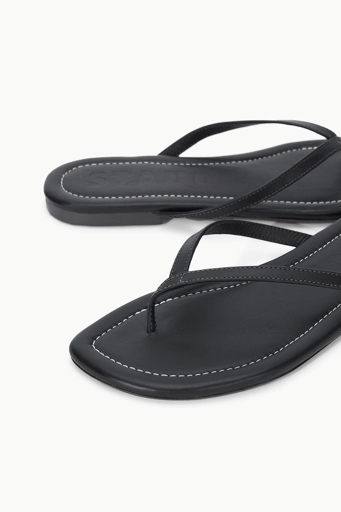 Black thong sandals, side view with contrast stitching along footbed