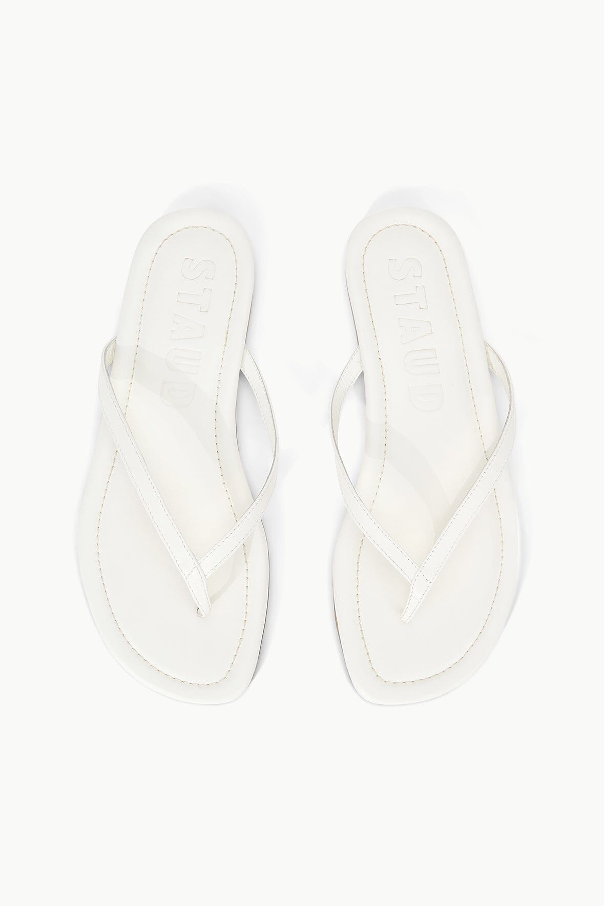 White thong sandals with crisscross straps and stitched edges, top view