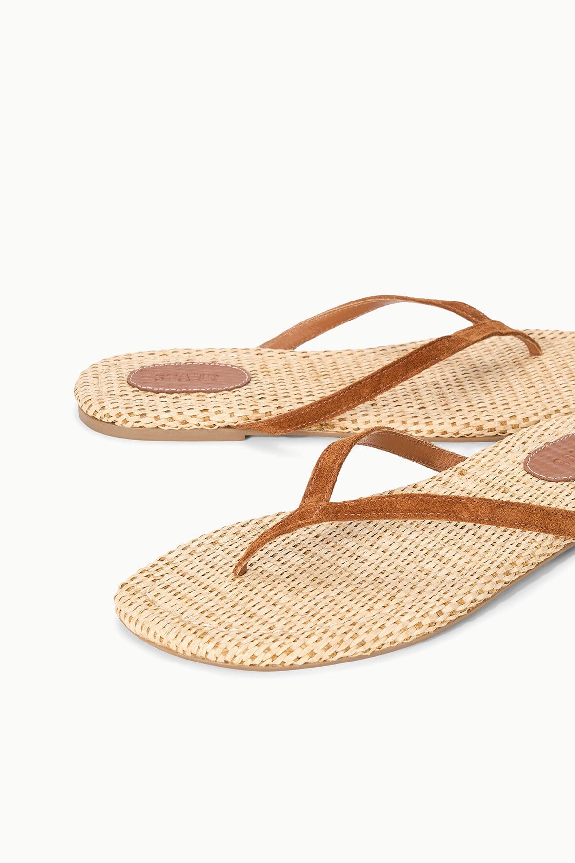 Pair of tan woven thong sandals with cross straps and cushioned-looking insole