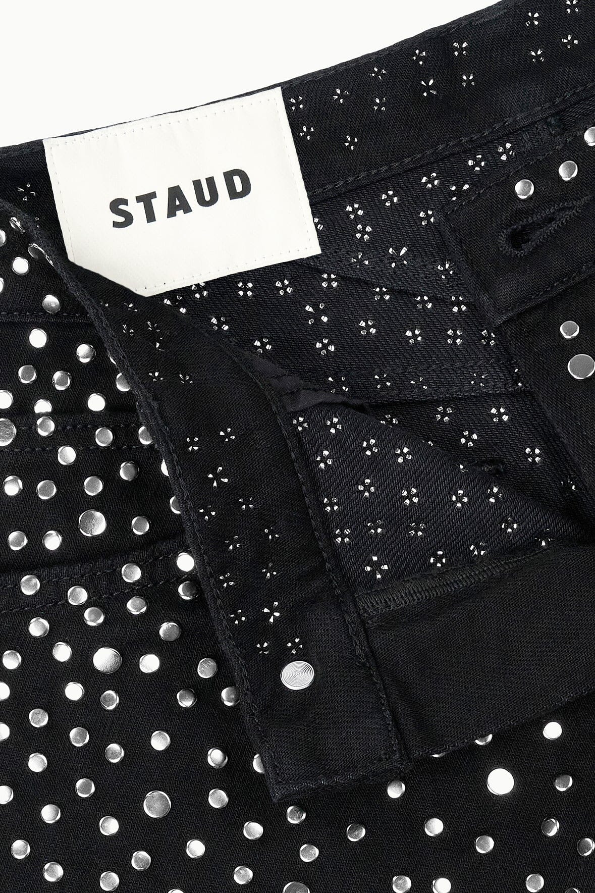Black jeans with STAUD label and silver stud pattern on the front panel.