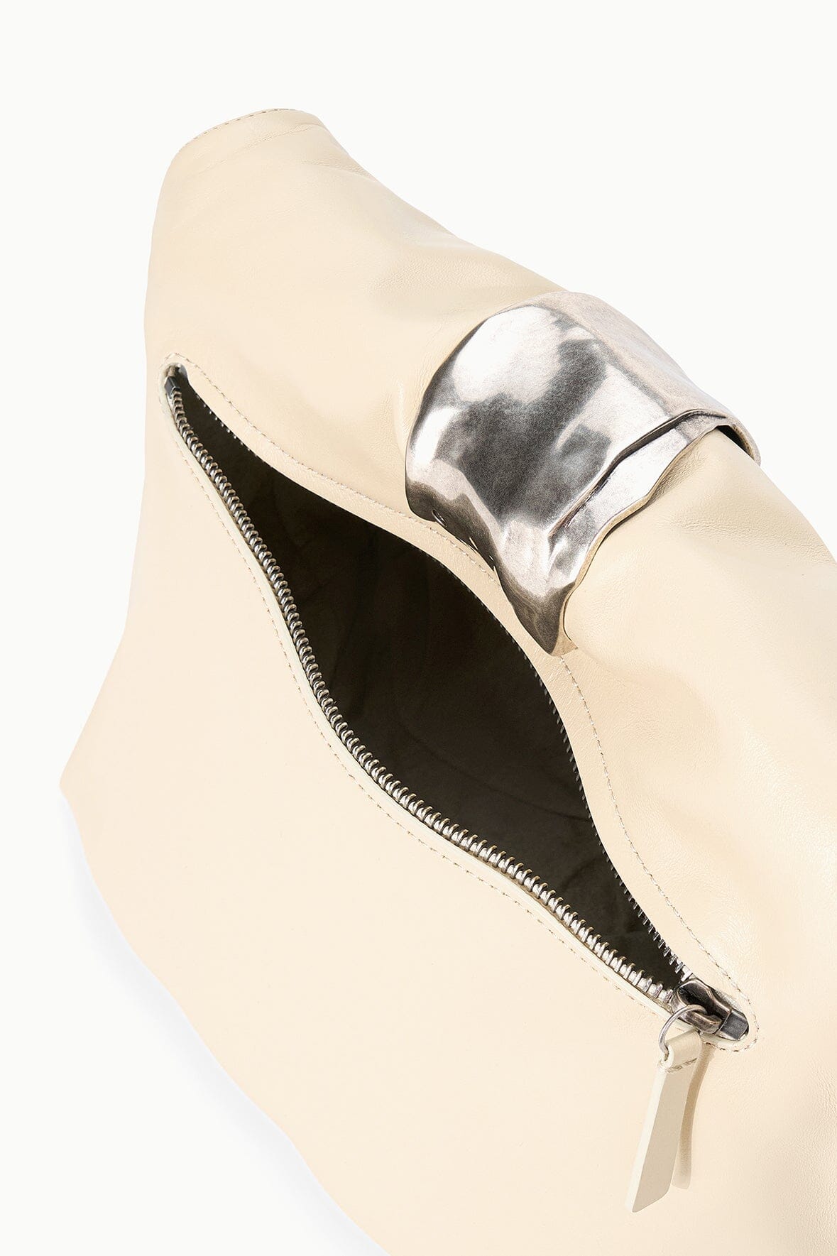 Cream cuff clutch with partially open zipper and dark interior lining.