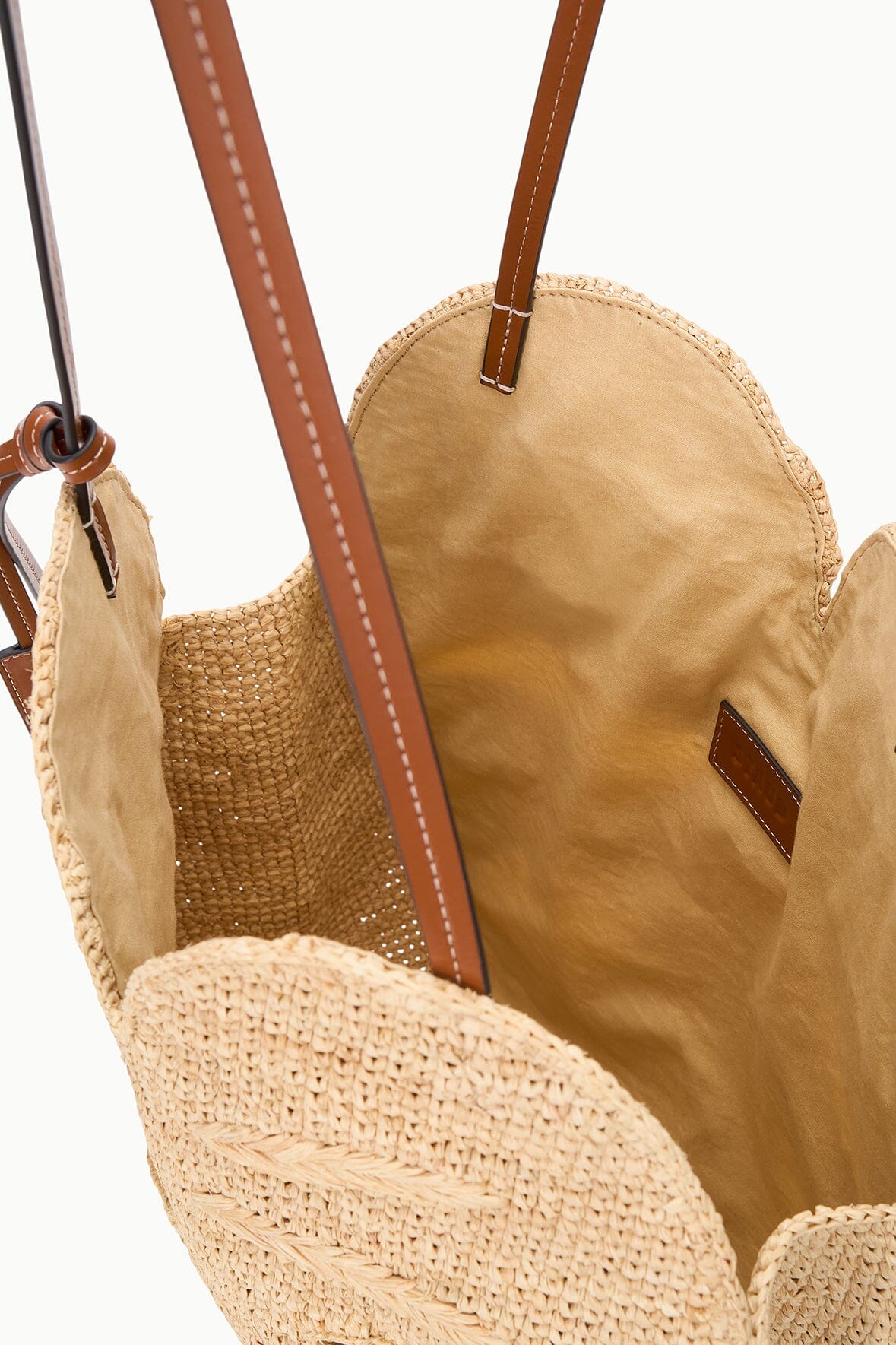 Natural raffia bag interior view with brown leather trim and top handle attachments