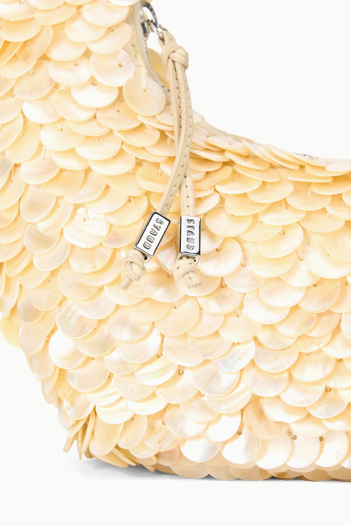 Cream scallop sequined shoulder bag with top handle and zipper pull, side view.