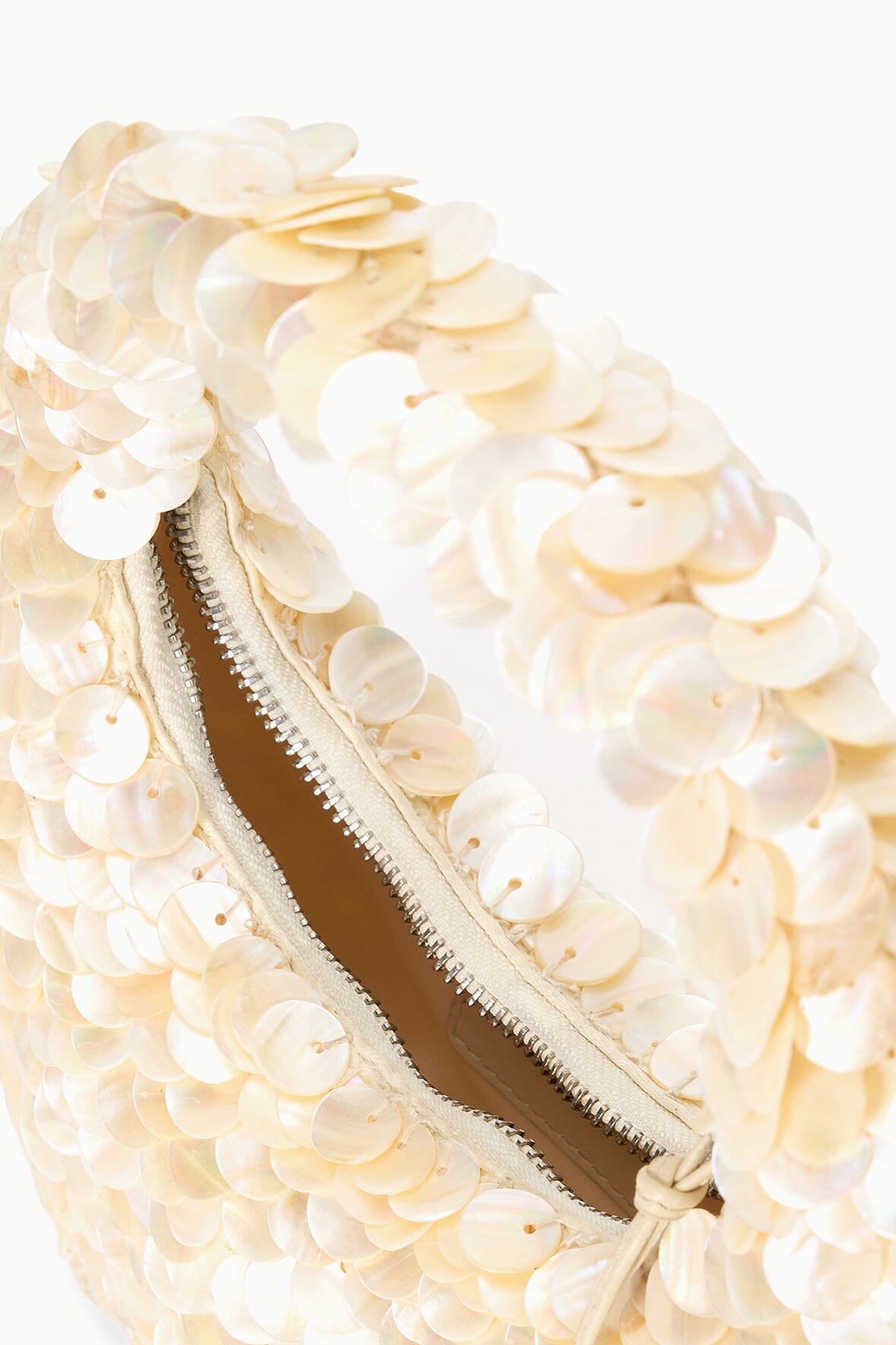 Cream sequined scallop bag with visible brown interior and zipper, close-up.
