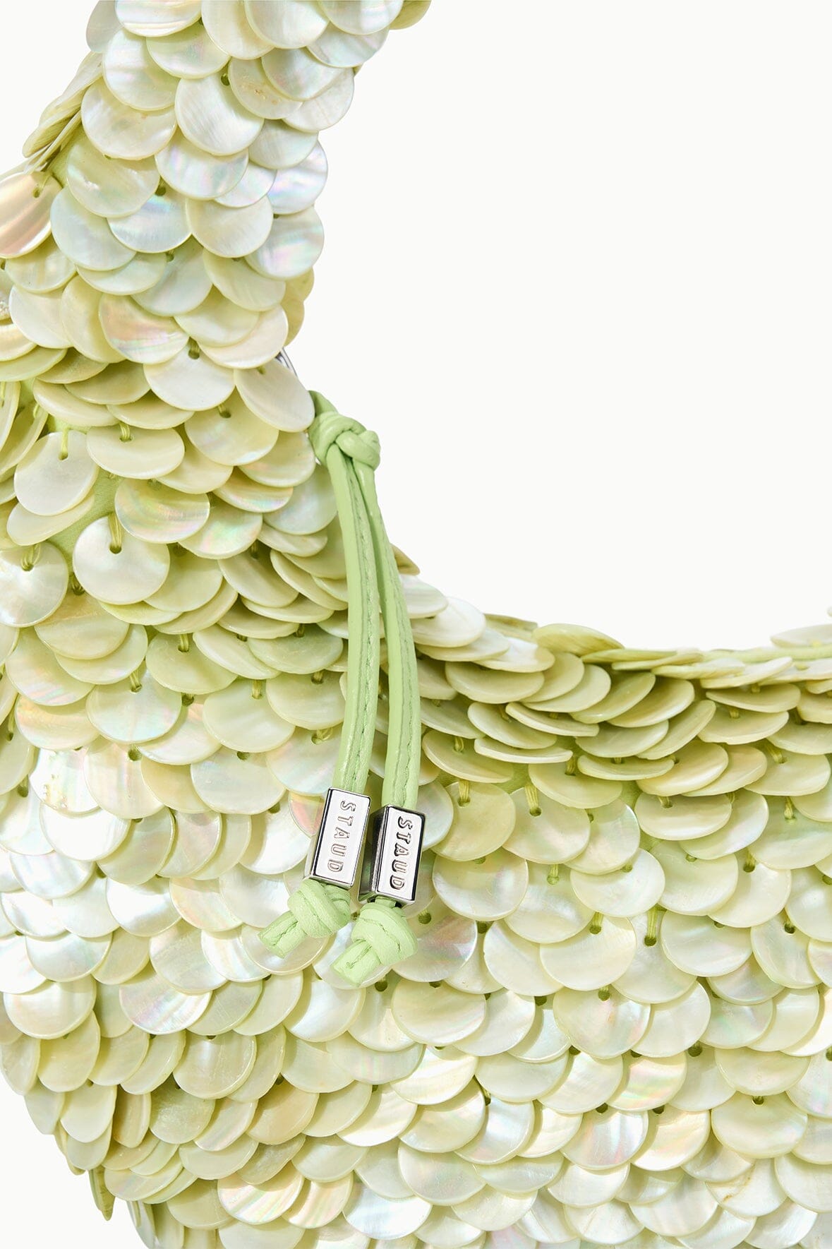 Light-green sequin-shell bag with green cord strap and rectangular clasp tags