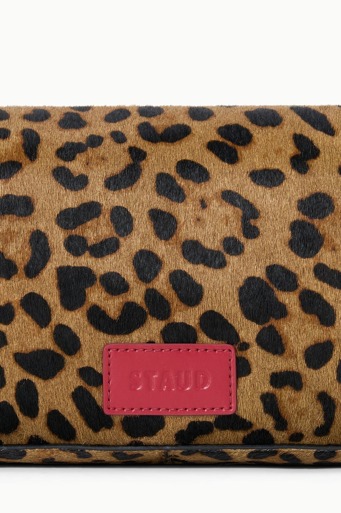 Cheetah-print flap bag detail with red logo patch and dark spotted pattern