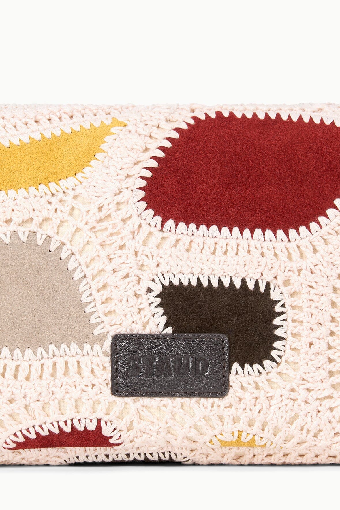 Woven patchwork bag closeup with dark leather logo label and suede panels