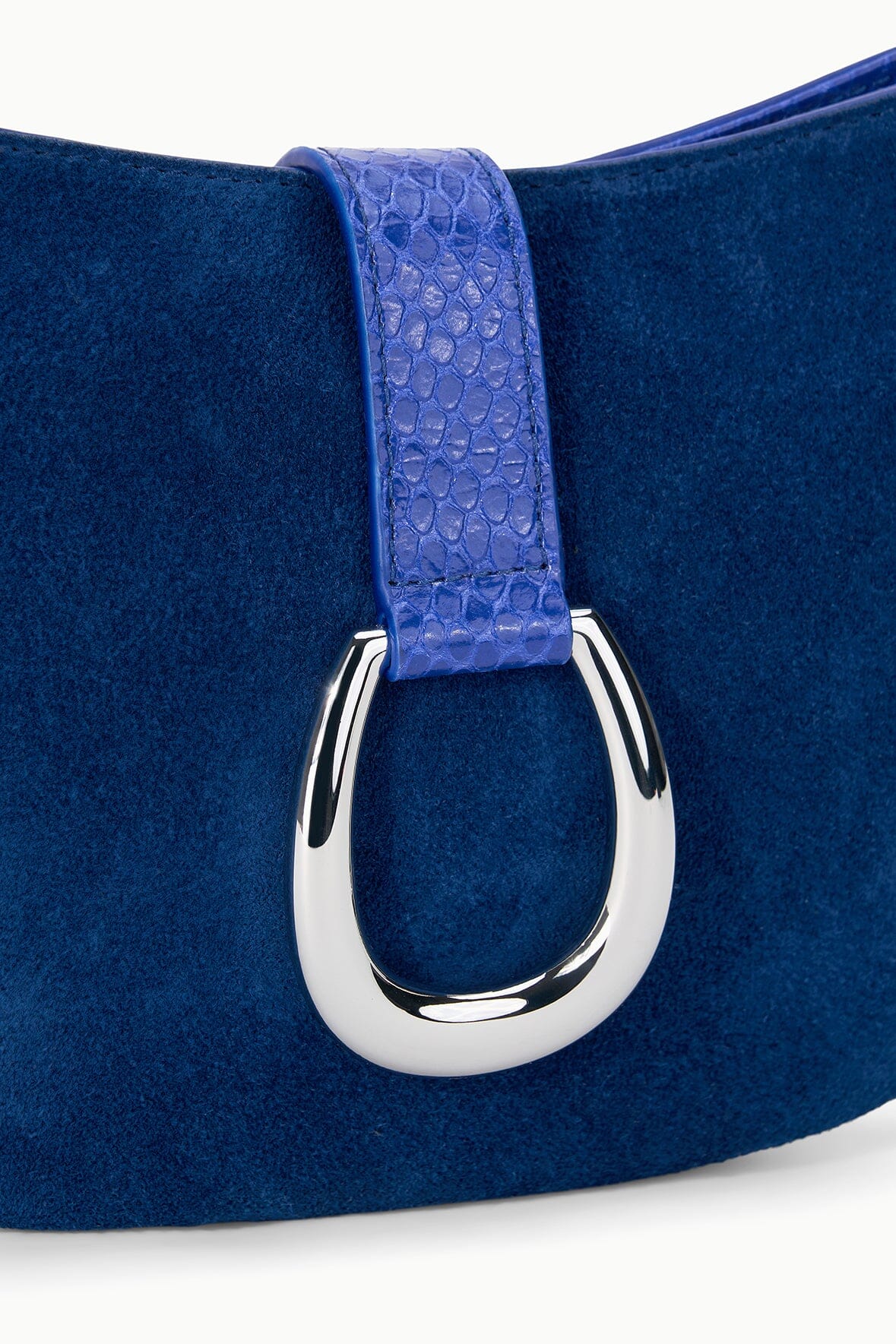 Cobalt suede shoulder bag close-up with silver ring buckle and textured strap