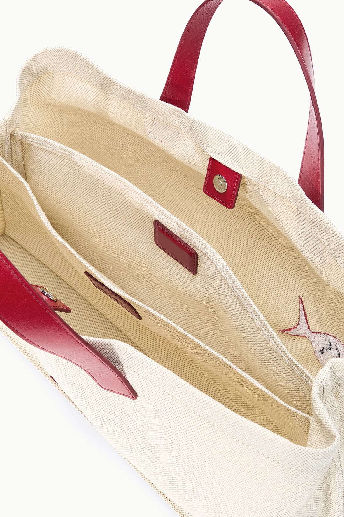 Cream canvas tote bag with red handles and inner slip pocket details