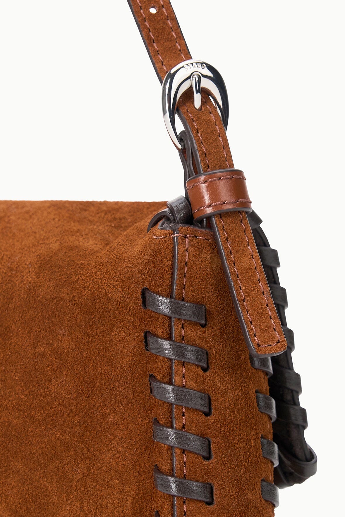 Suede bag strap detail with dark metal rings and layered buckle hardware