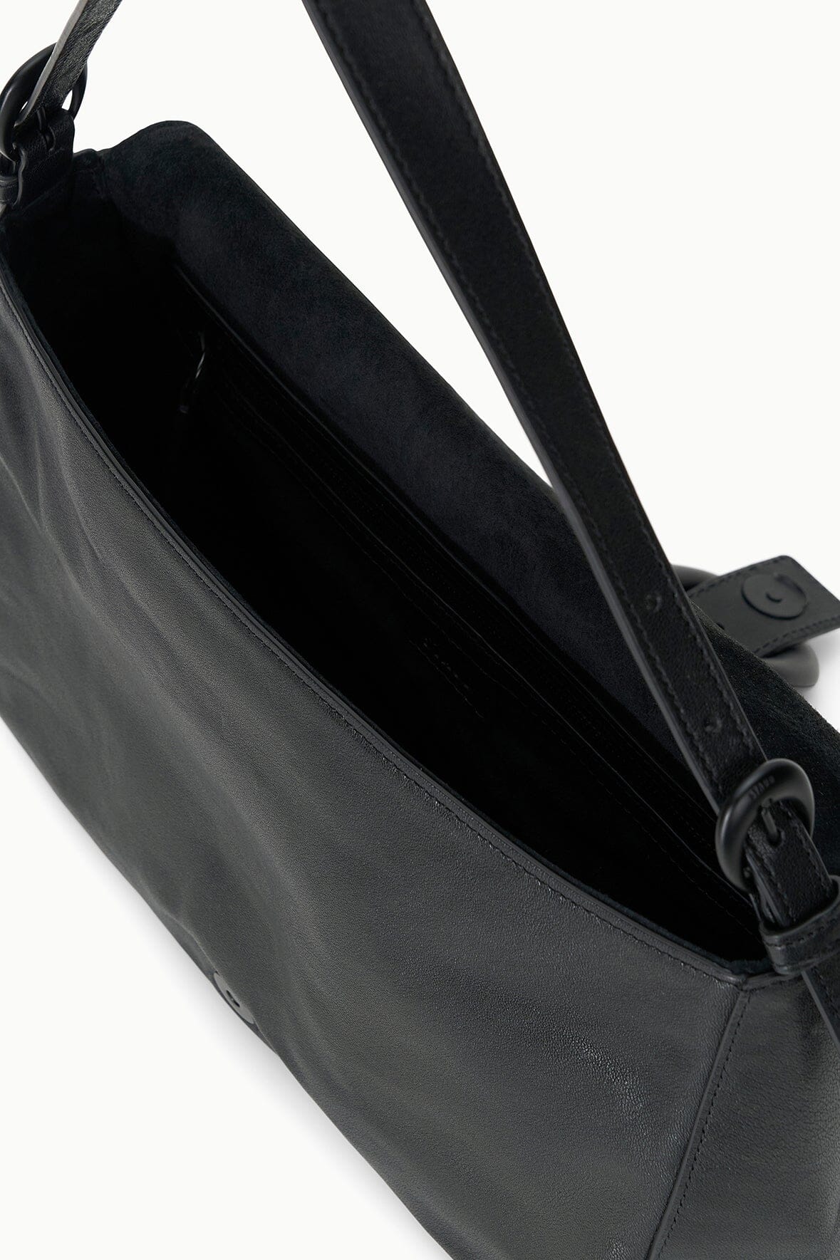 Black leather-look bag interior with adjustable shoulder strap and metal ring hardware