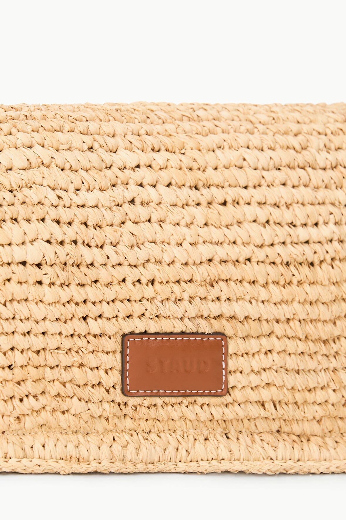 Raffia bag front panel with brown leather-look logo patch and stitched border