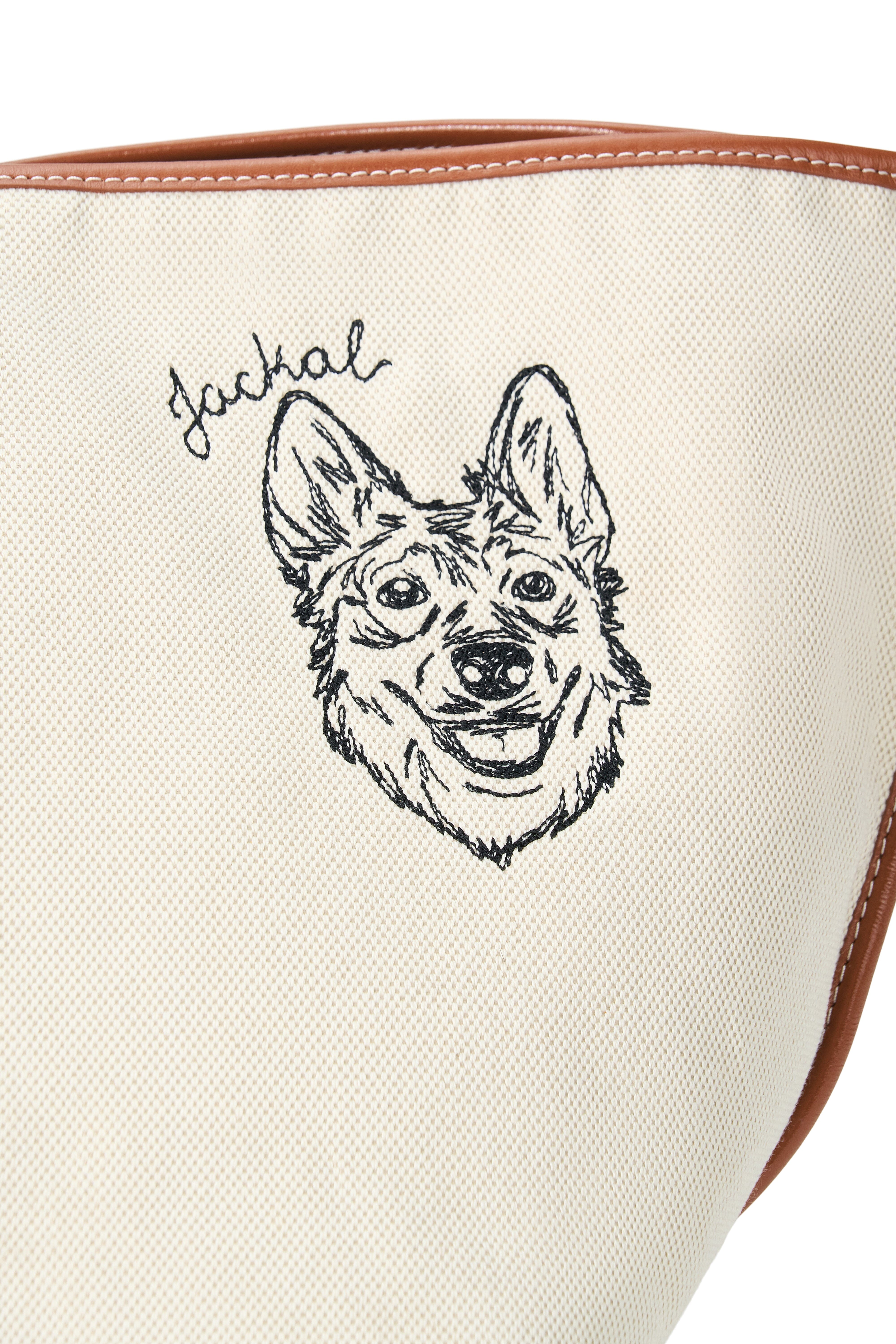 Cream canvas tote with black dog-face illustration and tan leather edge