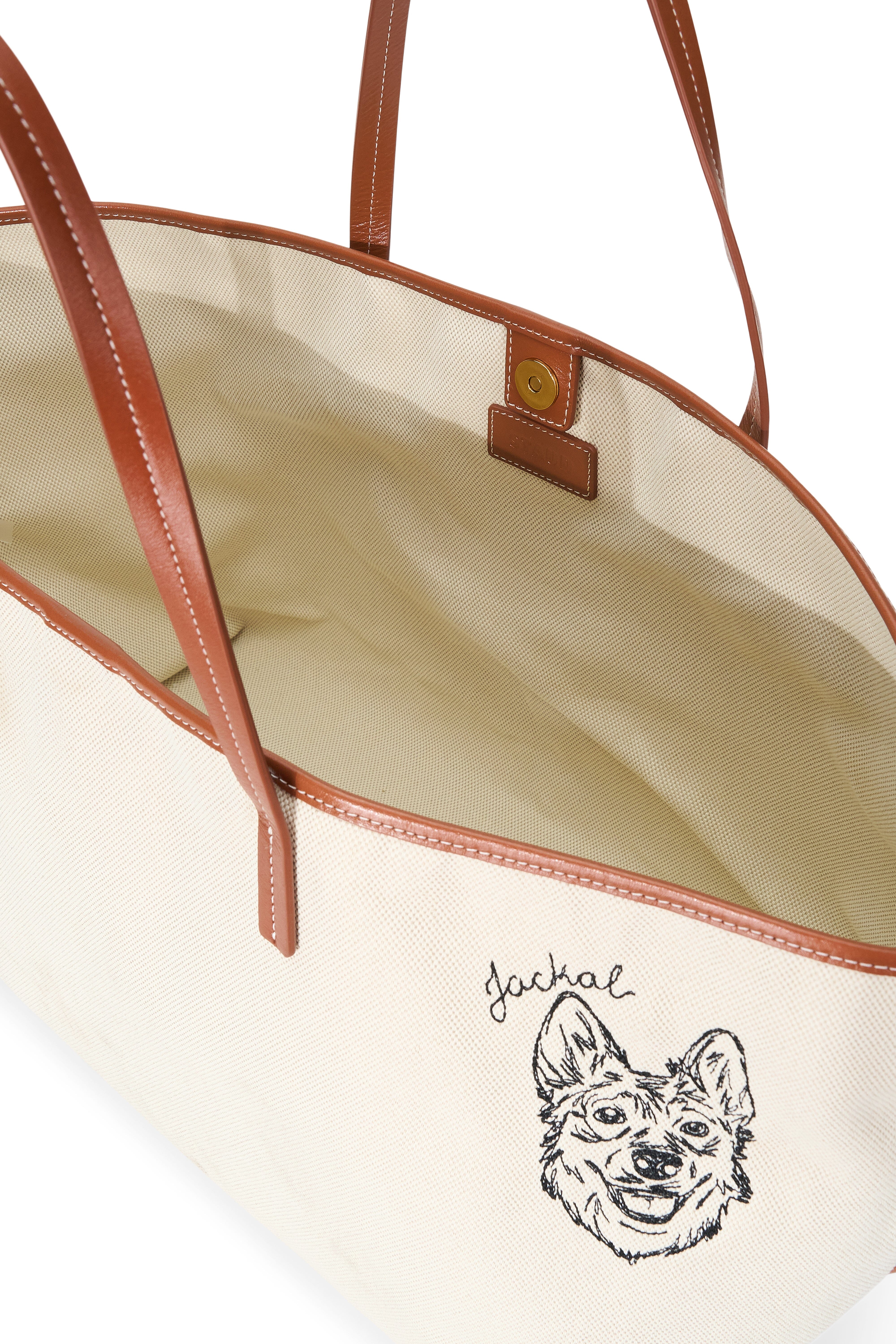 Cream canvas tote interior with tan straps, trim, and leather brand label
