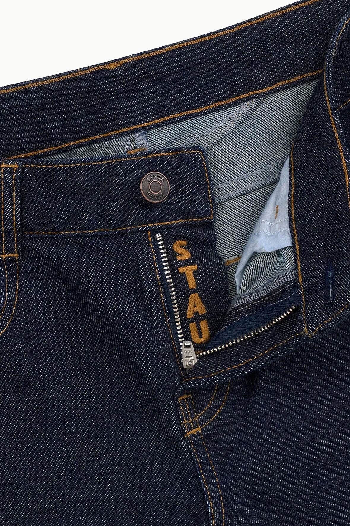 Indigo stretch jeans close-up of zipper fly and waistband interior with STAU D label