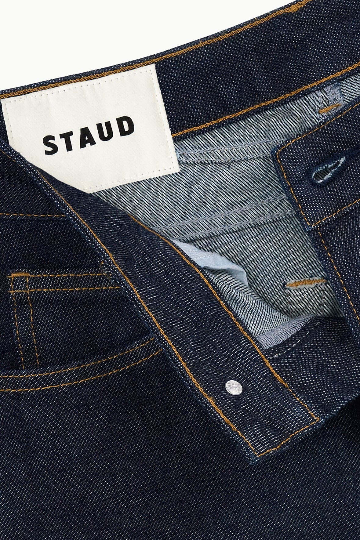 Indigo denim jeans with STAUD tag, button closure, and double row topstitching