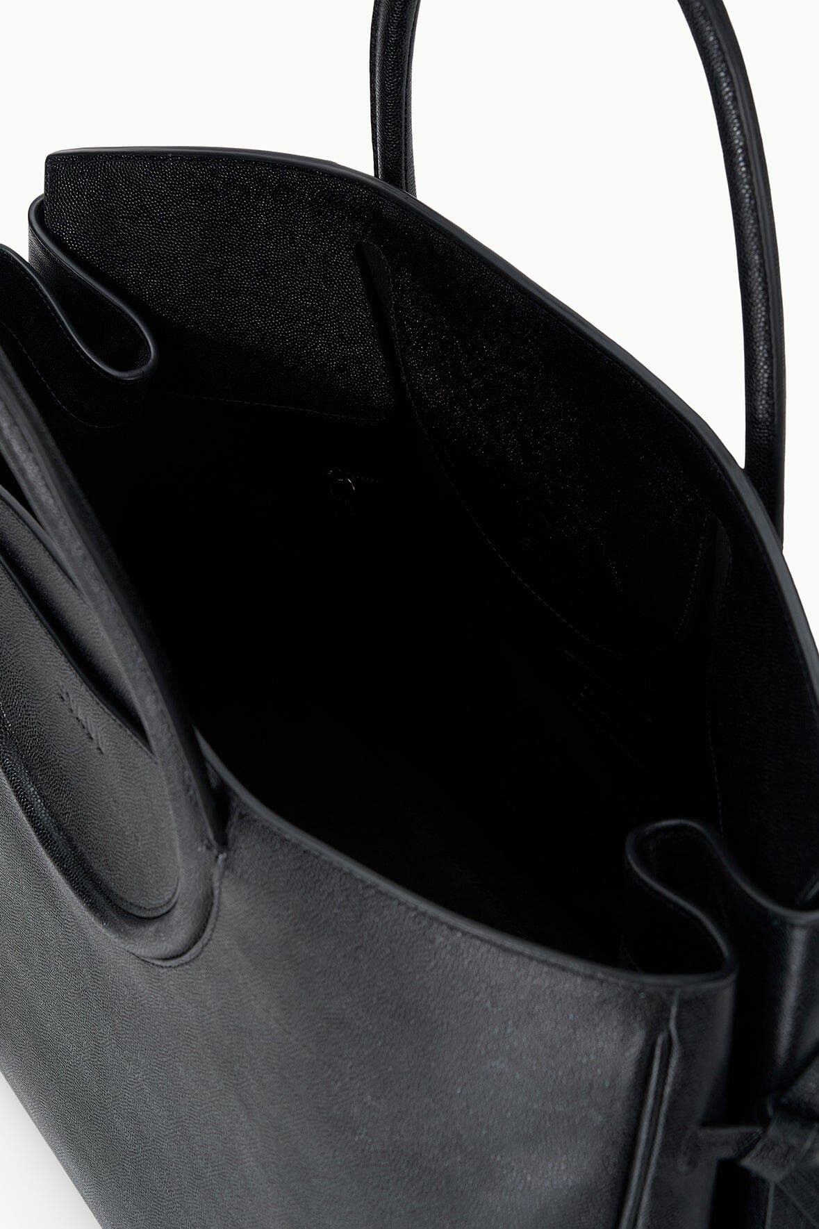 Black carryall handbag interior view with open top and side pocket