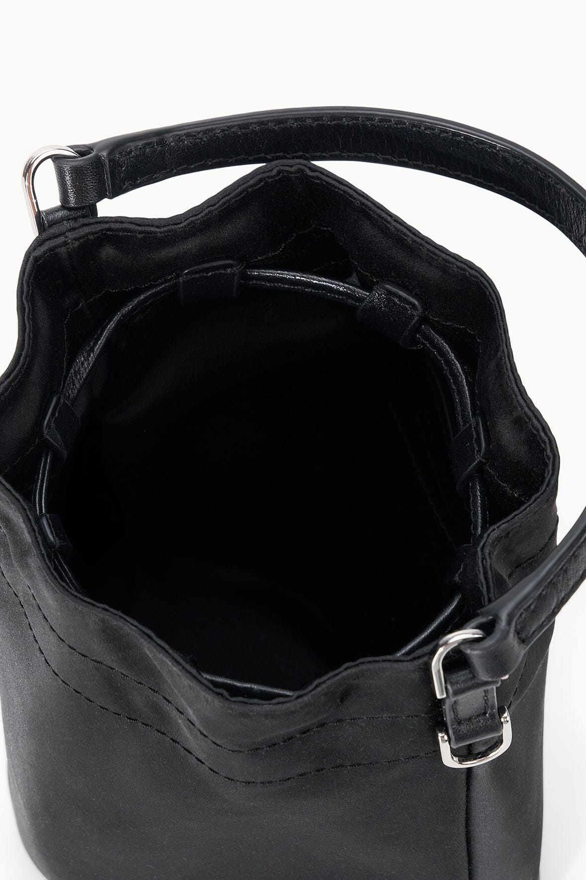 Black mini bucket bag interior view with drawstring and metal clasp at front