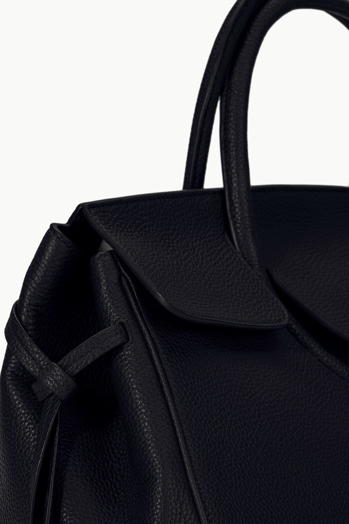 Maude carryall bag close-up in black with textured finish and front flap detail.