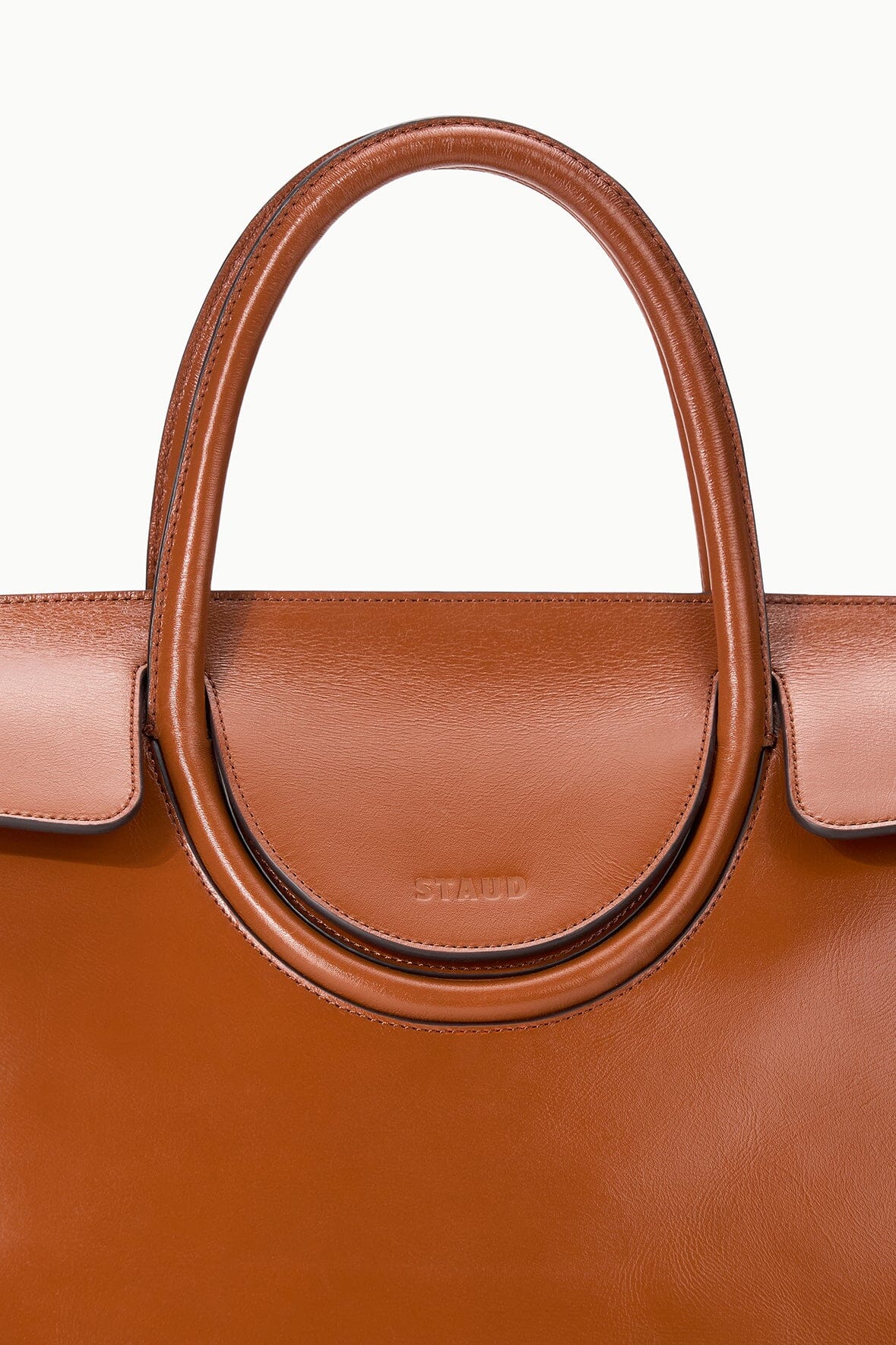 Tabac leather carryall bag handle with stitched oval detail and embossed logo center