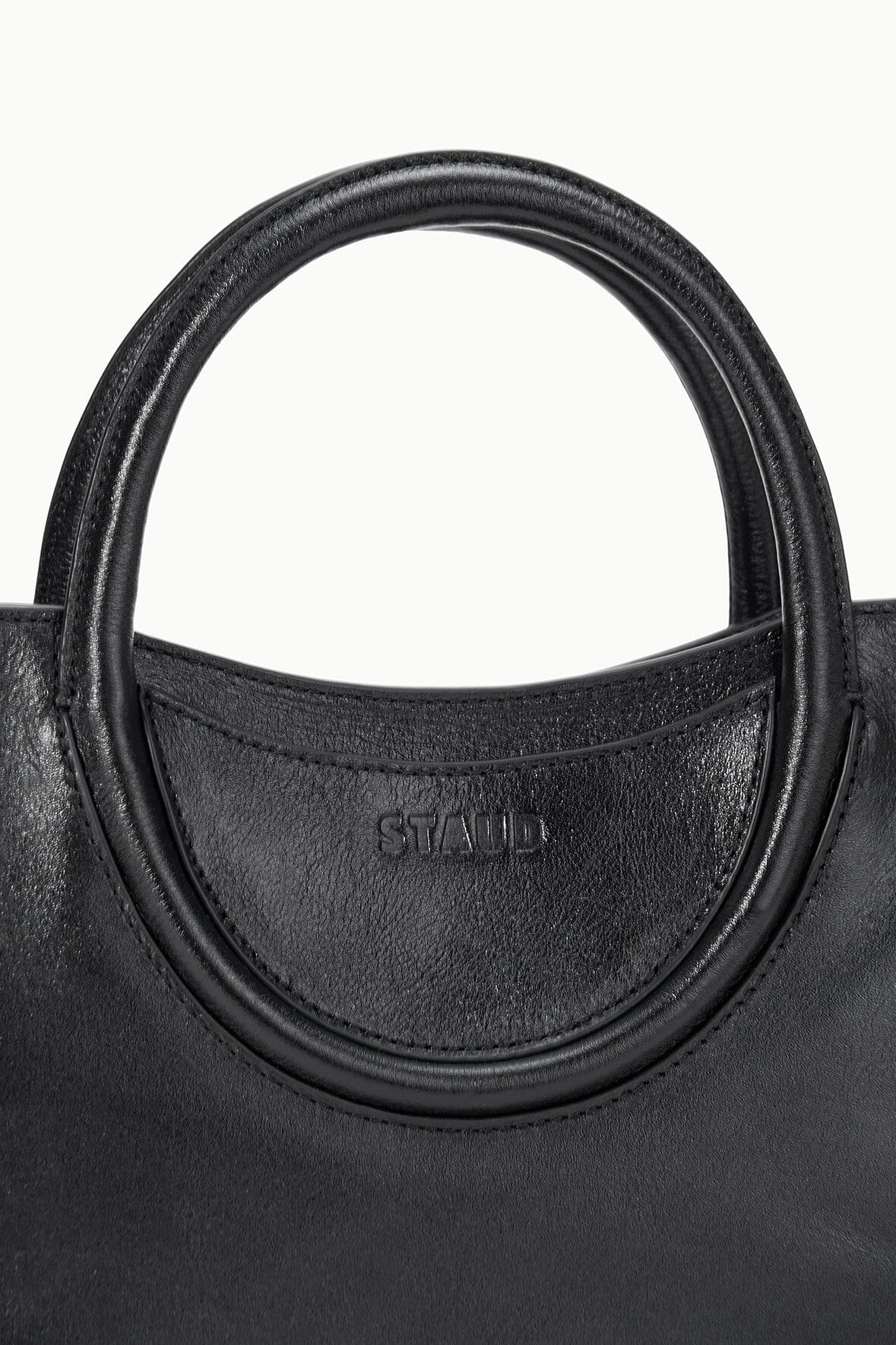 Black mini satchel bag handle base with embossed STAUD logo on the front