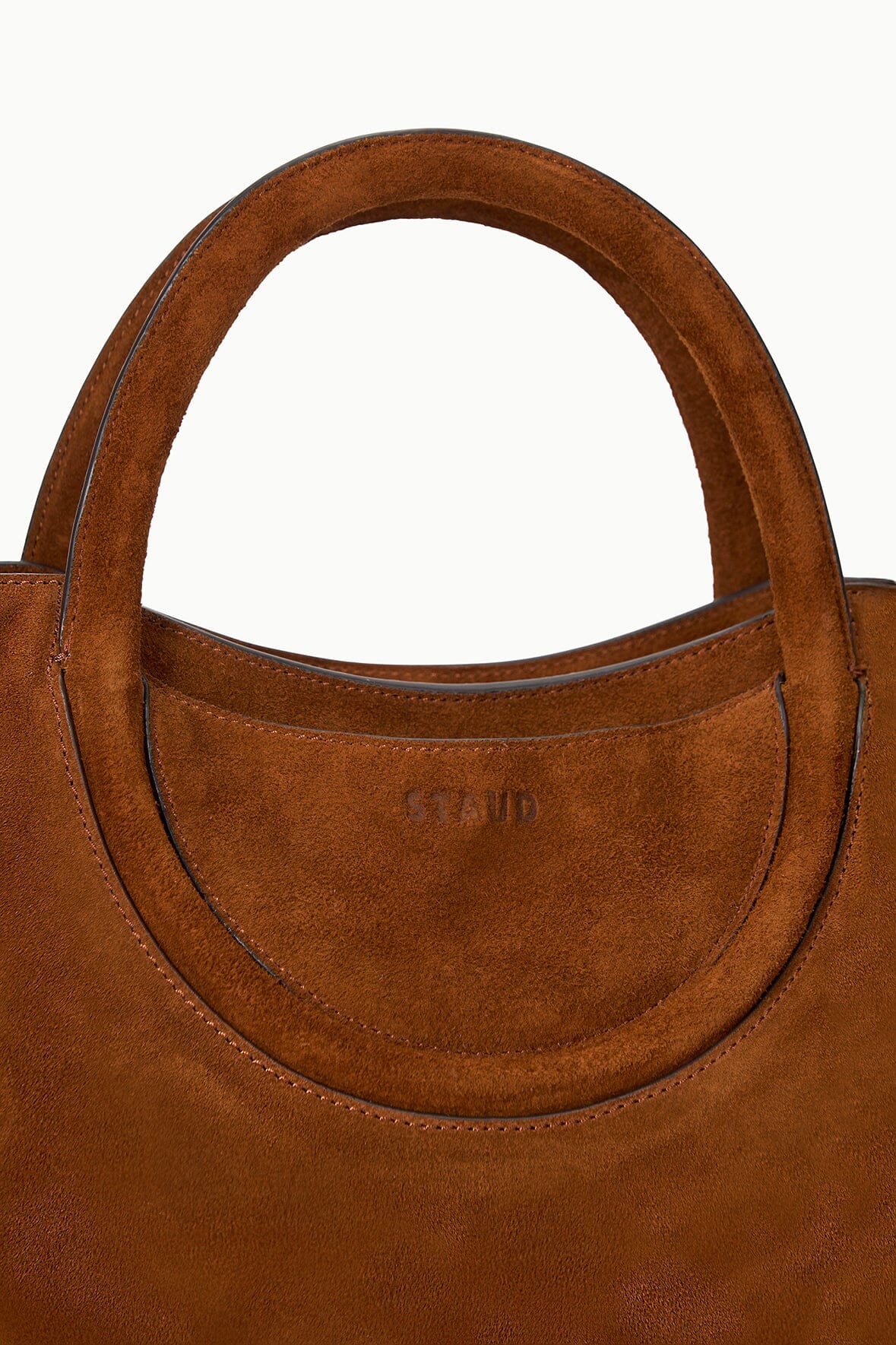 Brown suede satchel with rounded front yoke, stitched trim, and embossed logo