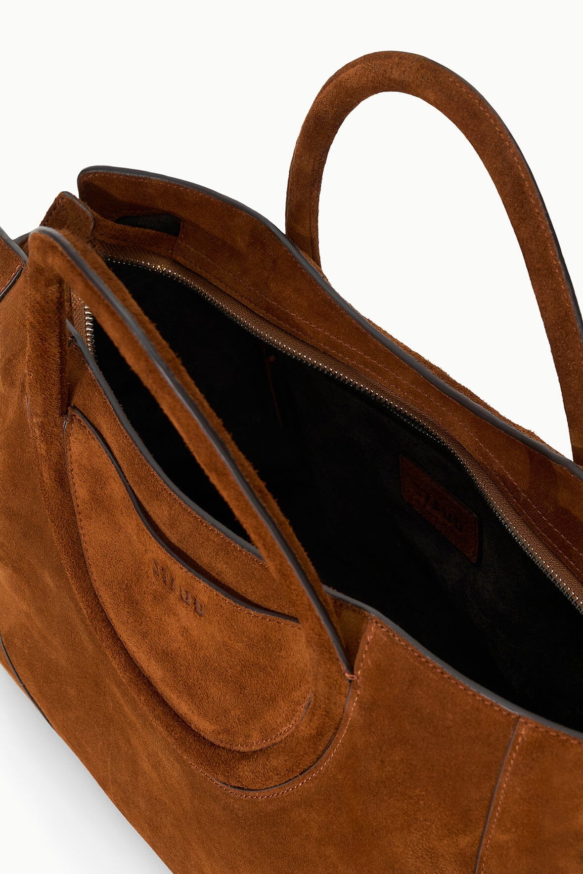 Suede satchel interior view with top zipper, side pocket, and dark lined compartment