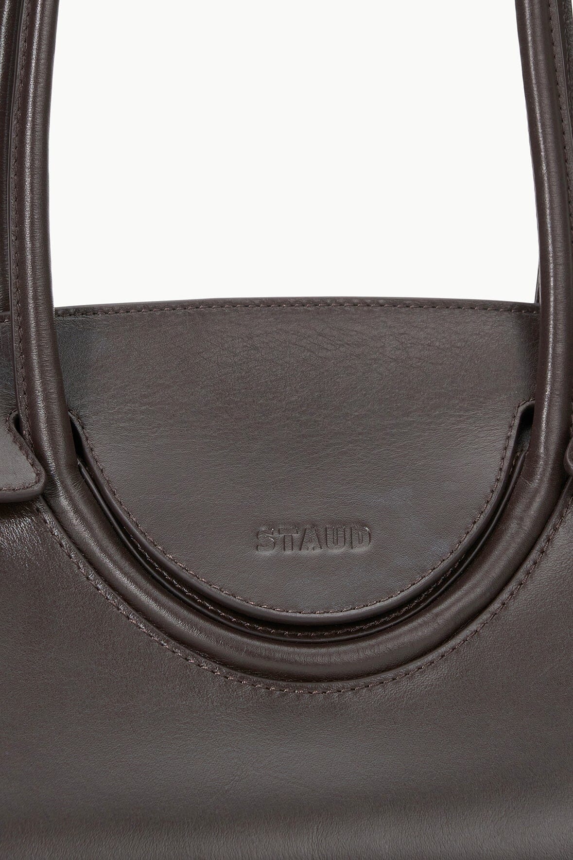 Espresso-brown leather shoulder bag close-up of front logo and curved seam