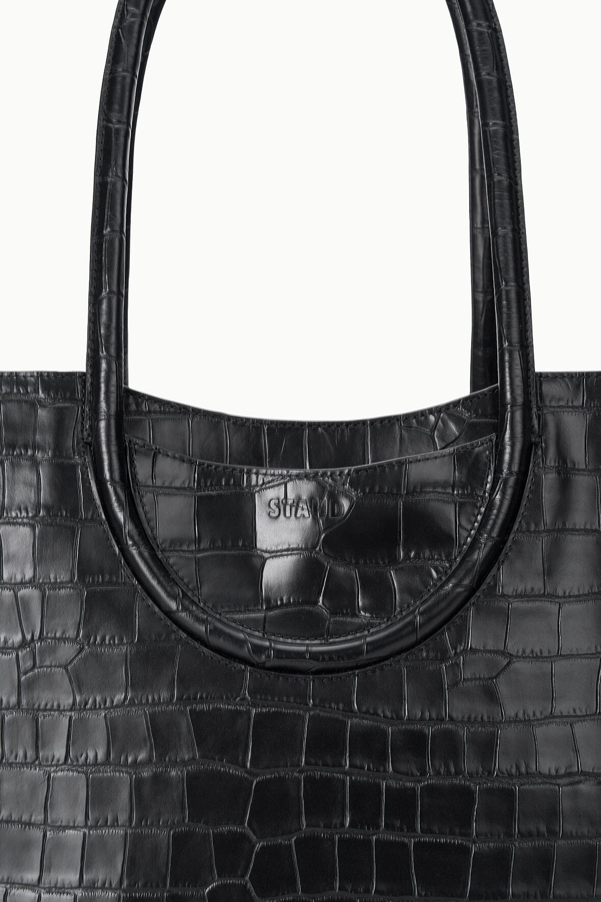 Black croc-effect tote bag front with curved opening and embossed logo patch.