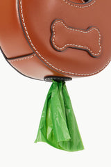 Tan poop bag carrier with bone applique and hanging green waste bag