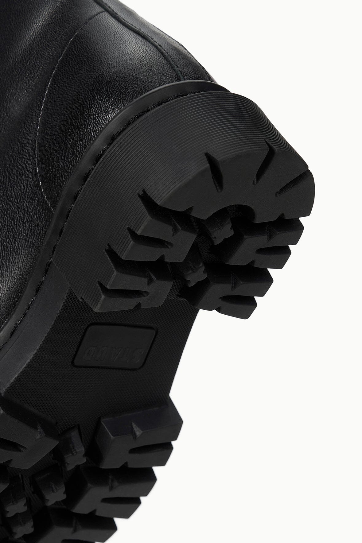 Black lug sole with deep tread and stitched side edge on black boot.