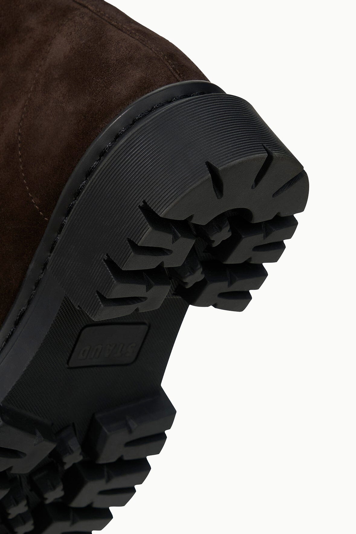 Chunky black lug outsole with tread on espresso suede ankle boot