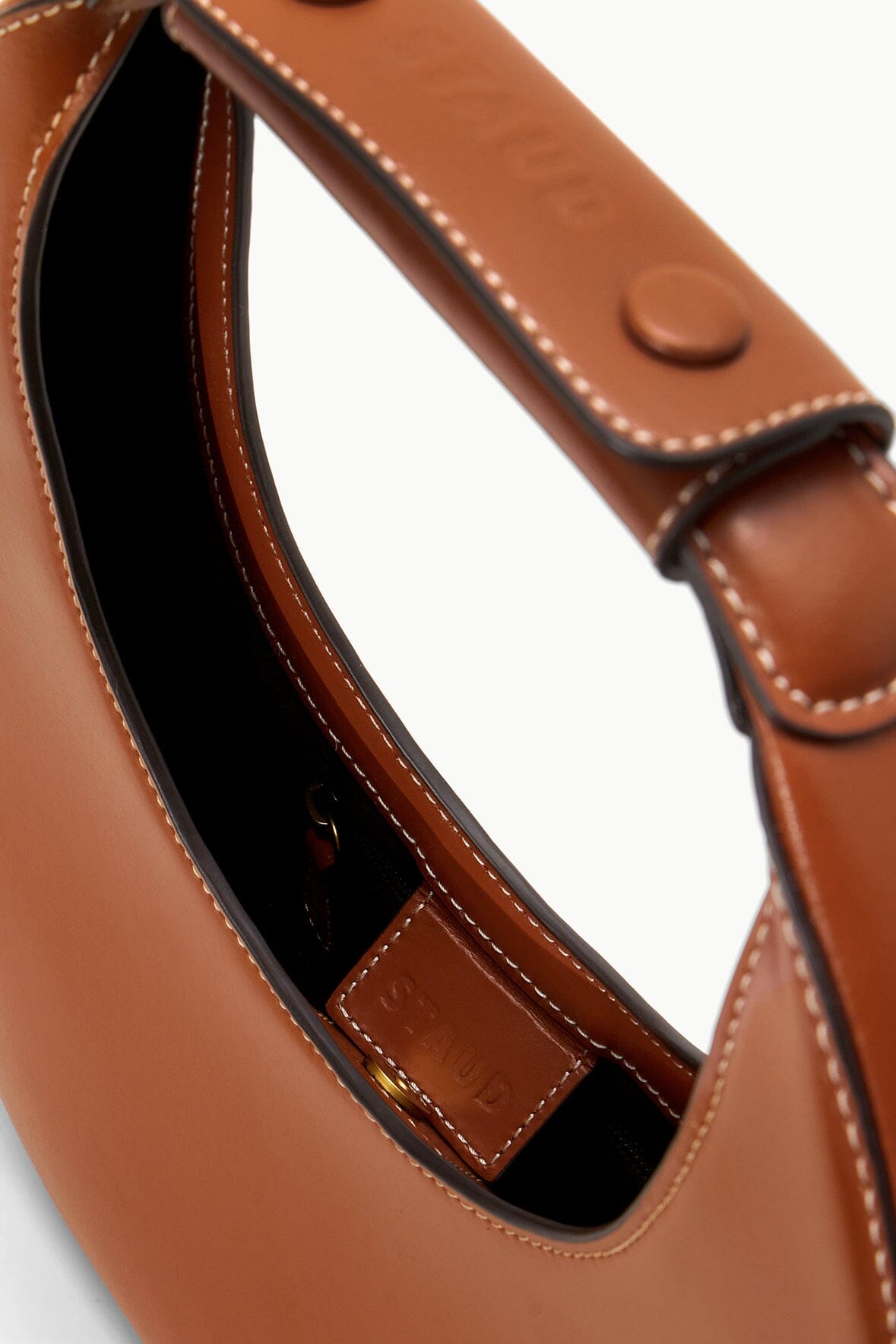 Saddle brown leather bag interior view with stitched strap tabs